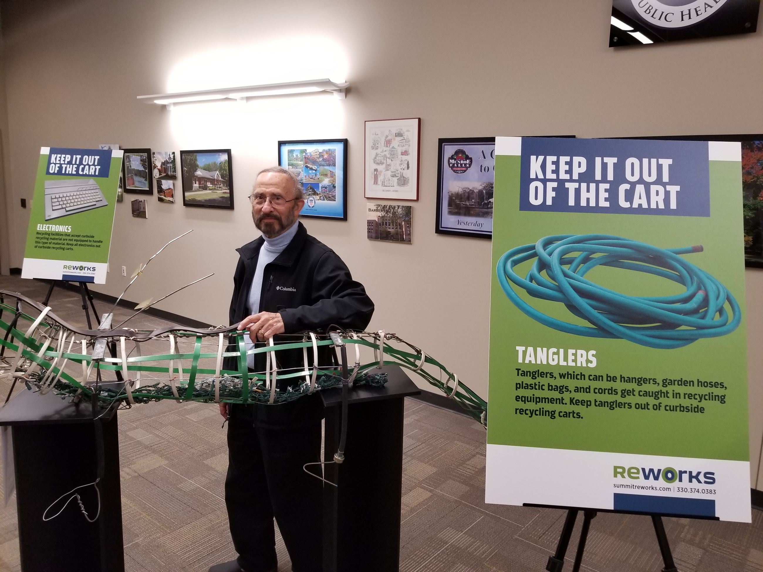 Dr. Charles Felzen Johnson displaying his sculpture of 'tanglers' beside a didactic panel